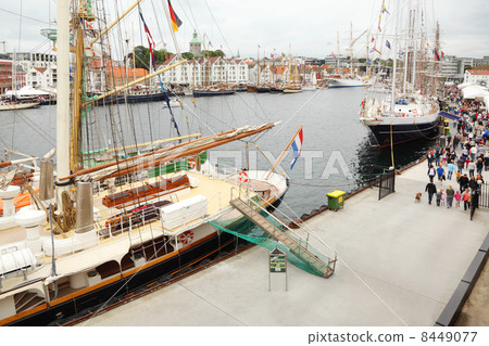 Sailboats with colorful flags stand at pier; people walk; top vi 8449077