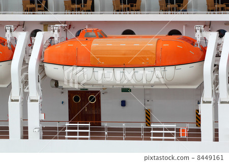 Orange lifeboat installed on large white passenger liner deck 8449161