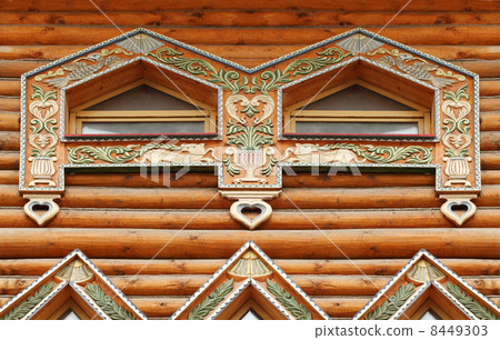 Fragment of large wooden house with carved decoration and two wi 8449303