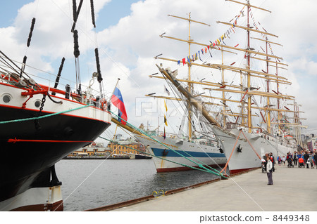 Beautiful sailboats with colorful flags stand at pier; people wa 8449348