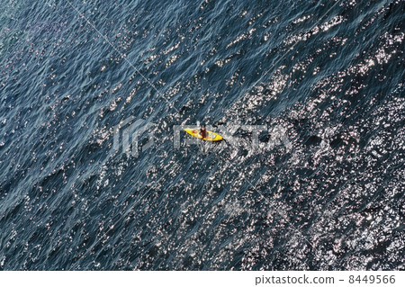 Man rows oar in little yellow kayak floats on open sea; top view Man rows oar in little yellow kayak floats on open sea; top view 8449566