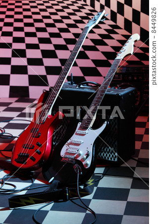 Two electric guitars and sound amplifying equipment on checkerbo 8449826