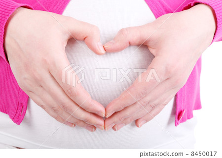 Hands of pregnant woman wearing in pink blouse depicting heart o 8450017