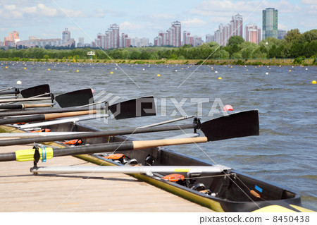 Long sport boat with oars stands at wooden pier at background of 8450438