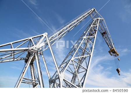 big white hoisting crane with hook at background of blue sky big white hoisting crane with hook at background of blue sky 8450590