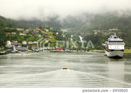 NORDDAL - JUNE 26: Cutter floats to shore with coastal village u 8450685