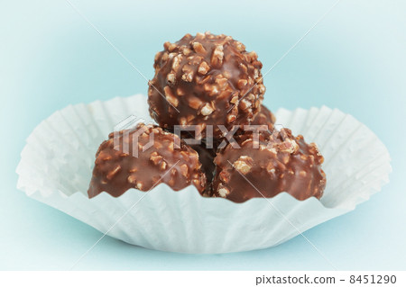 Group chocolate candies in a white paper basket. On a blue backg Group chocolate candies in a white paper basket. On a blue backg 8451290
