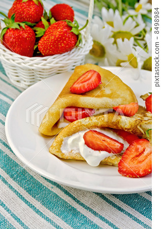 Pancakes with strawberries and basket with berries on a napkin 8498984