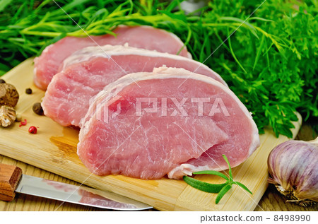 Meat pork slices on a board with greens Meat pork slices on a board with greens 8498990