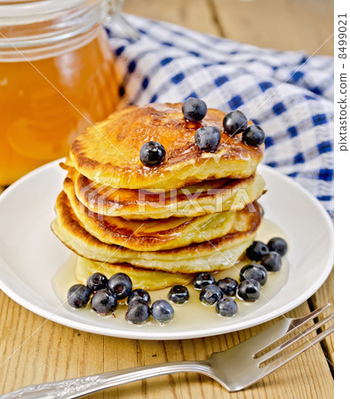Flapjacks with blueberries and a jar of honey on the board 8499021