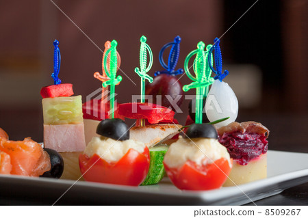 Dish with delicious canapes on skewers, close-up 8509267