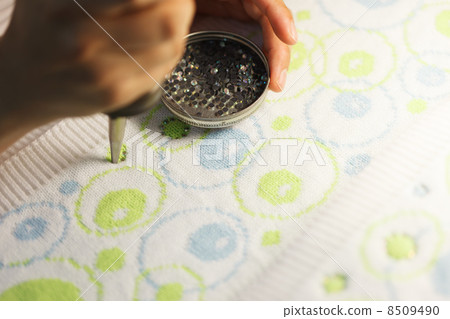 Woman glueing sequins to colorful fabrics 8509490