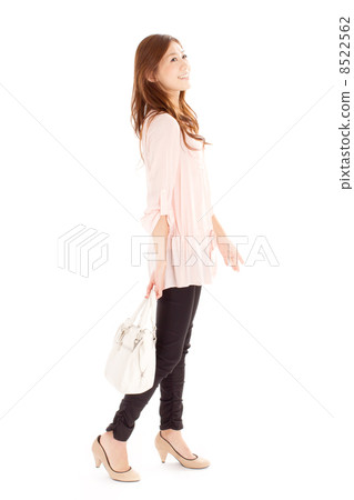 A cool-looking woman in middle of walking with a handbag in hand A cool-looking woman in middle of walking with a handbag in hand 8522562