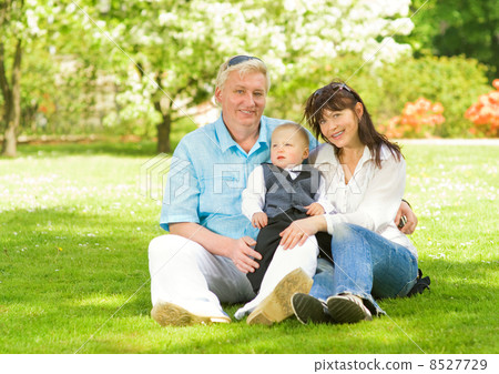 Happy family sitting on a meadow in park 8527729