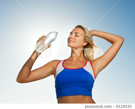 Young woman drinking water after fitness exercise Young woman drinking water after fitness exercise 8528585
