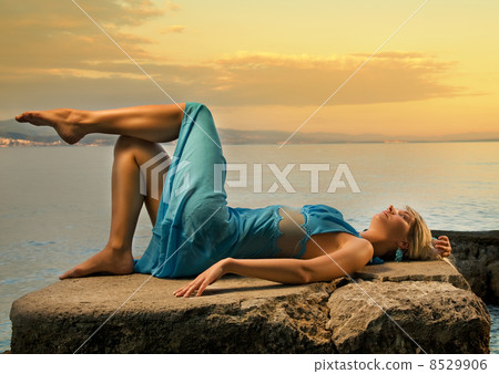 Stock Photo: Young woman relaxing near the sea - Stock Image - Everypixel