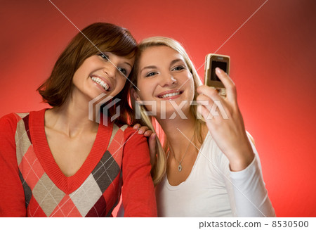 Two beautiful girls making self-portrait using mobile phone Two beautiful girls making self-portrait using mobile phone 8530500