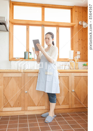 A housewife with a tablet in the kitchen A housewife with a tablet in the kitchen 8564567