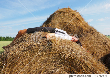 Woman on hay bale in summer field 8576991