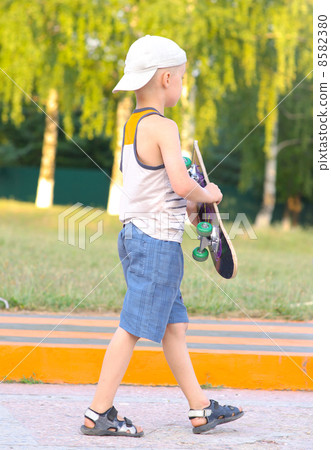 Boy Child going with Skateboard behind view Outdoor Summer Sport with nature on background Boy Child going with Skateboard behind view Outdoor Summer Sport with nature on background 8582380