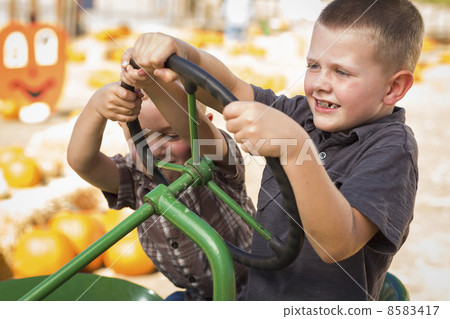 Adorable Young Boys Playing on an Old Tractor Outside Adorable Young Boys Playing on an Old Tractor Outside 8583417