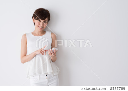 一個操作智能手機的年輕女子 一個操作智能手機的年輕女子 8587769