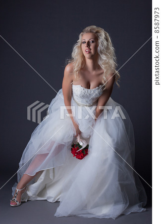 Elegant curly-haired bride posing in studio 8587973