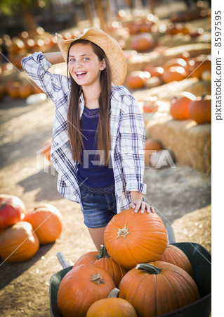 Preteen Girl Playing with a Wheelbarrow at the Pumpkin Patch. Preteen Girl Playing with a Wheelbarrow at the Pumpkin Patch. 8597595