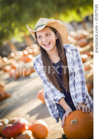 Preteen Girl Playing with a Wheelbarrow at the Pumpkin Patch. 8597598
