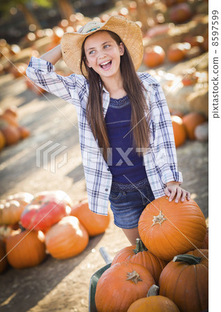 Preteen Girl Playing with a Wheelbarrow at the Pumpkin Patch. Preteen Girl Playing with a Wheelbarrow at the Pumpkin Patch. 8597599