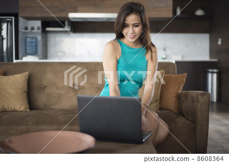 Woman sitting on sofa using laptop Woman sitting on sofa using laptop 8608364