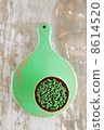 green peppercorns in bowl on green wooden board 8614520