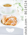 Croissant with coffee, on sunlit breakfast tray 8614524