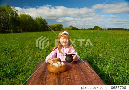 little girl drinking milk on a wooden table 8627708