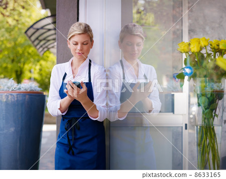 Young woman working as florist in shop and text messaging 8633165