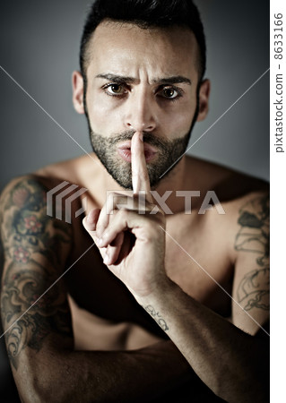 tattooed man with finger on mouth 8633166