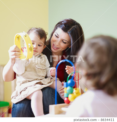 two little girls and female teacher in kindergarten 8634411