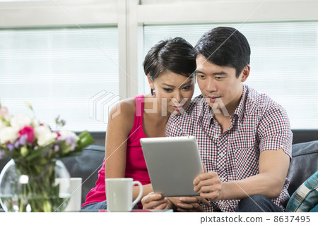 Young Chinese couple using a digital tablet Young Chinese couple using a digital tablet 8637495