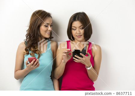 Two happy Asian women using there smartphones. 8637711