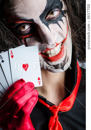Evil clown with cards in dark room 8657708