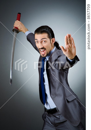 Angry businessman with sword in dark room 8657709