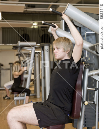 Young man using an exercise machine 8683248