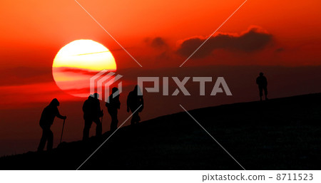 Group of tourists take to the mountains at sunset. Silhouette Group of tourists take to the mountains at sunset. Silhouette 8711523