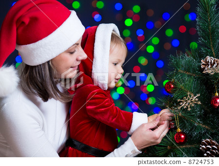 baby girl with mother decorating Christmas tree on bright backgr 8724753