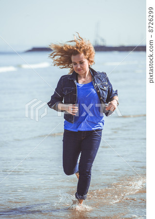 Young woman walking alone on the beach Young woman walking alone on the beach 8726299
