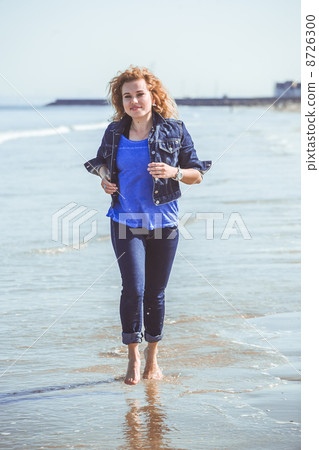 Young woman walking alone on the beach Young woman walking alone on the beach 8726300