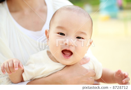 有一個微笑的嬰孩在一位母親在公園舉行了 8728712
