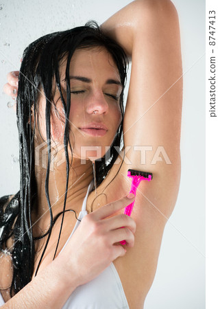 Portrait of young female shaving her armpit Portrait of young female shaving her armpit 8747413