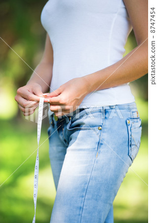 Healthy unrecognizable woman measuring waist Healthy unrecognizable woman measuring waist 8747454