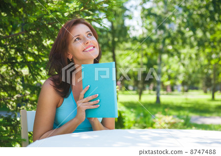 Positive adult woman reading book outdoors Positive adult woman reading book outdoors 8747488
